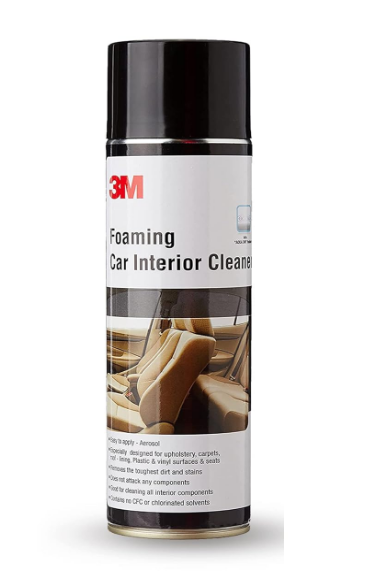 3M foaming car interior cleaner aerosol canister demonstrating high-density clinging foam action on a dark interior vehicle seat panel.